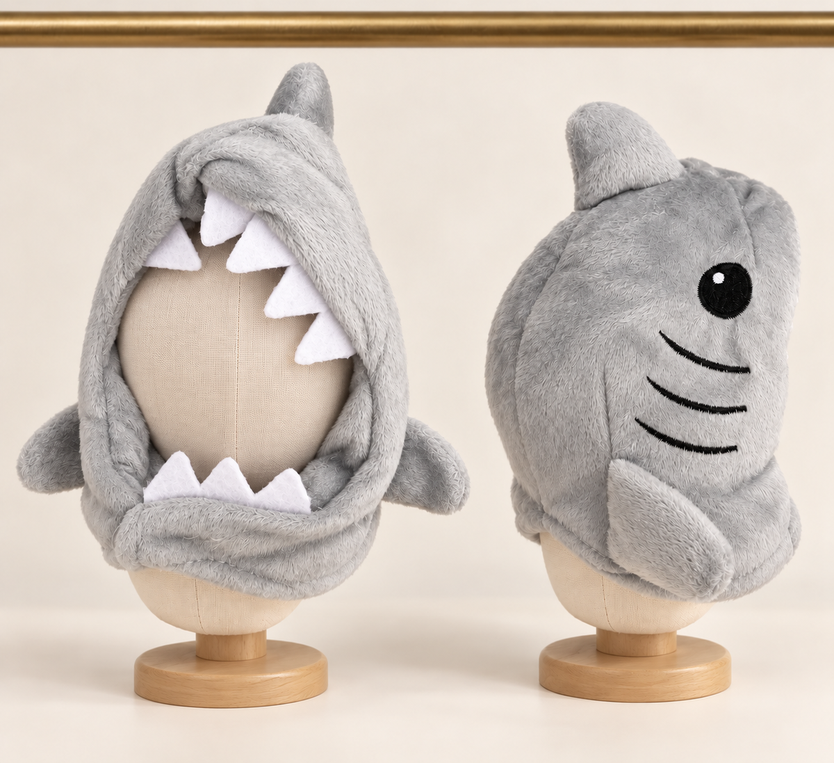 Grey plush shark hood for pets with white felt teeth around the face, a dorsal fin and an embroidered eye